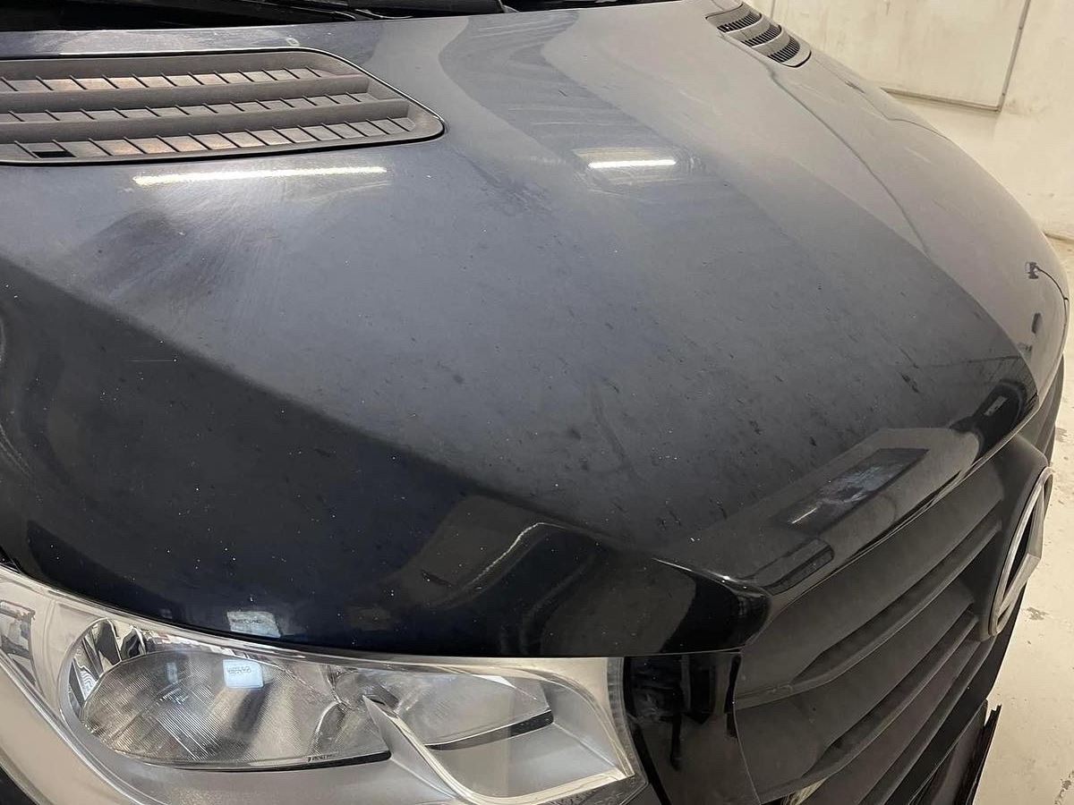 Sort motorhjelm på en varebil med mat lak, pletter og fine ridser før polering