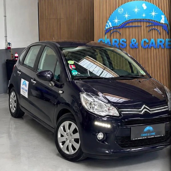 Mørkeblå Citroën C3 med Cars & Care-nummerplade på det lyse gulv i værkstedet